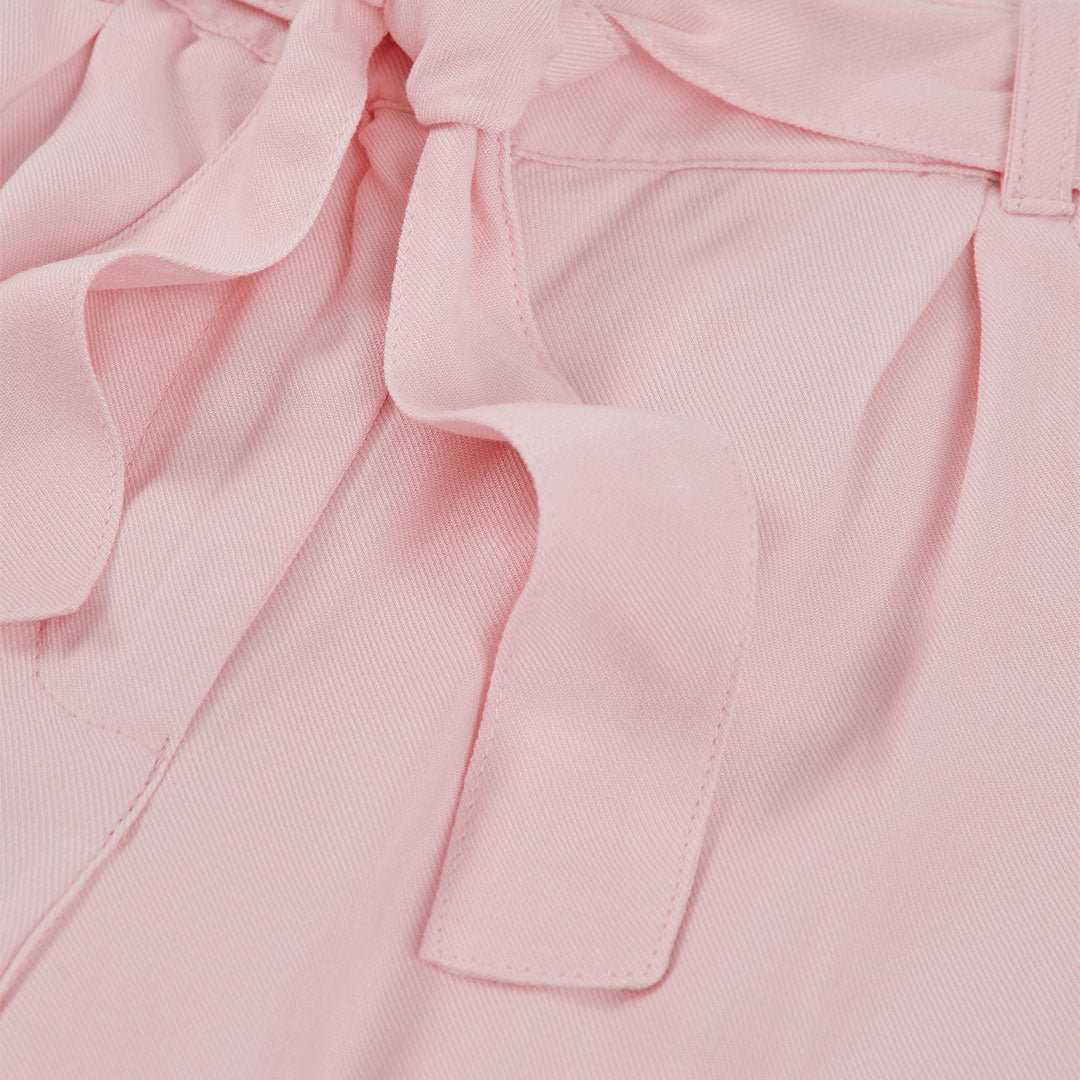Detail van strikceintuur en plooien op roze culotte broek